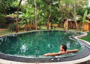 Een buitenzwembad, een infinitypool en ligstoelen