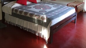 A bedroom with a large bed, a smaller bed, a tapestry, and a hanging light fixture. - Sat Nam Village Hotel (Avudangawa)