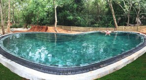 Een buitenzwembad, een infinitypool en ligstoelen