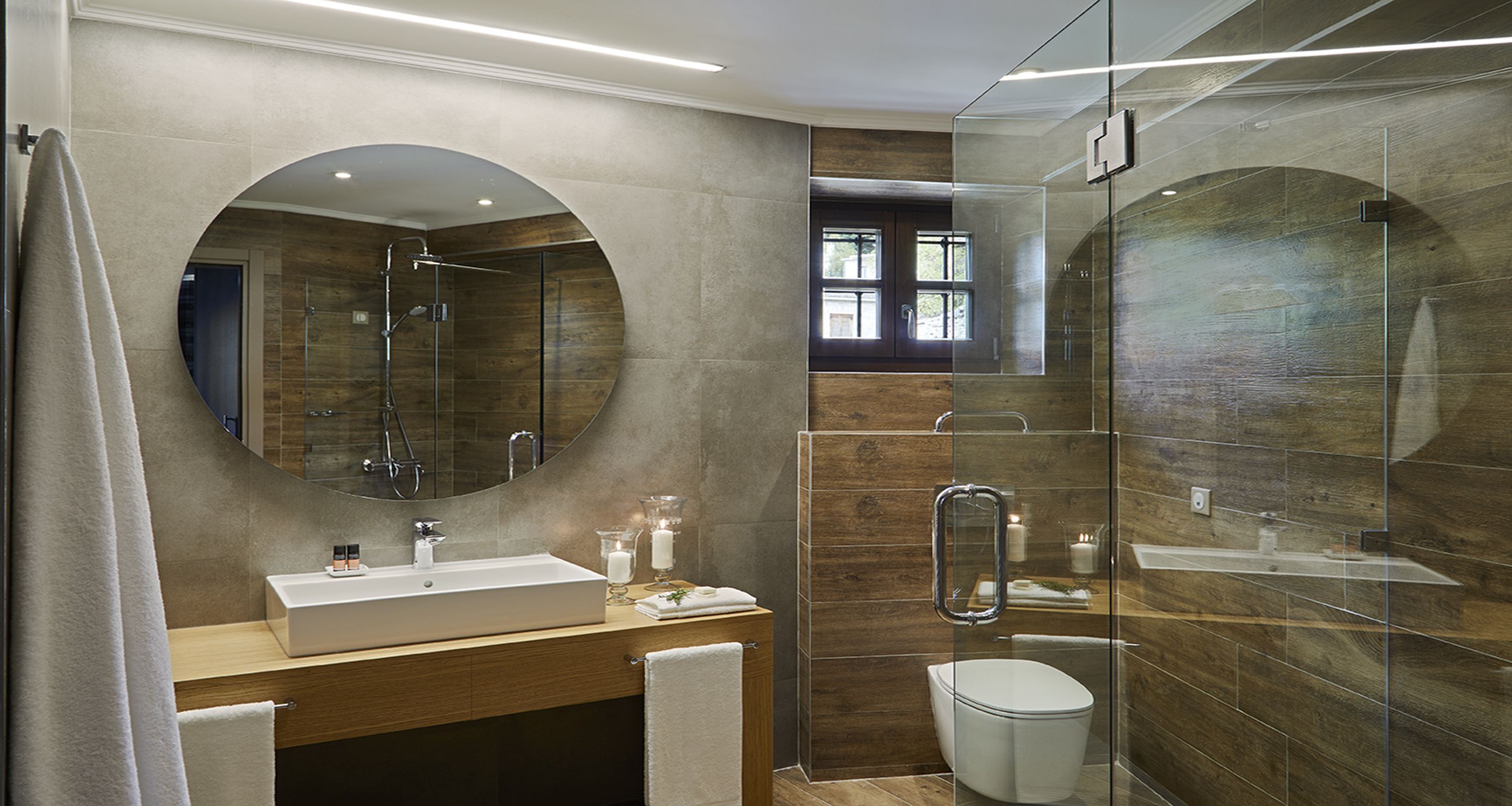 Un baño moderno con un espejo grande, un lavamanos, un inodoro y una zona de ducha.