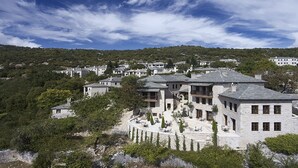 A hillside property with multiple stone buildings, some with balconies, surrounded by trees and greenery. - MounTrace Suites & Spa (Zagori)