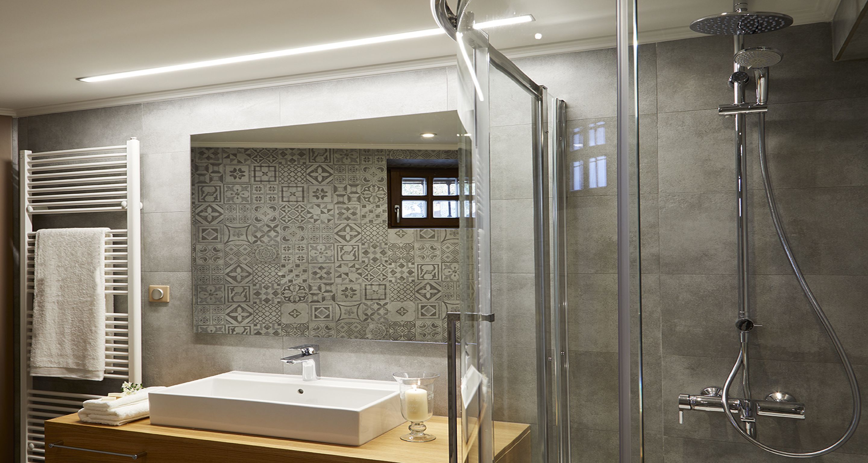 A modern bathroom with a glass-enclosed shower, a large mirror, and a tiled backsplash.