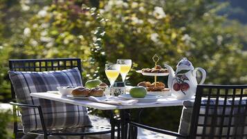An outdoor dining table with breakfast items, a pitcher, and a glass of orange juice.