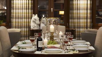 A dining table set for a meal with plates, glasses, a bottle of wine, and a candle.