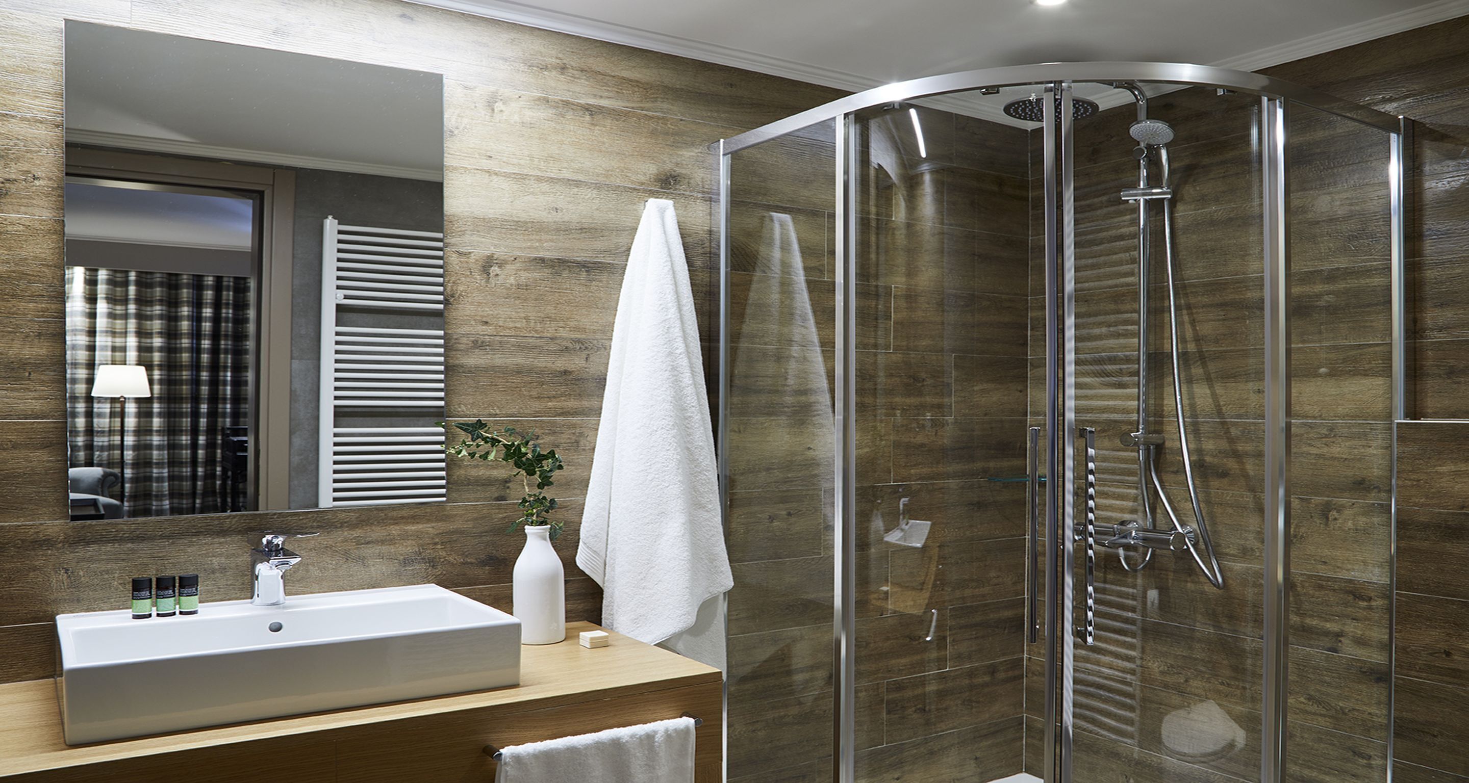 A modern bathroom with a glass-enclosed shower, a wooden vanity, and a large mirror.