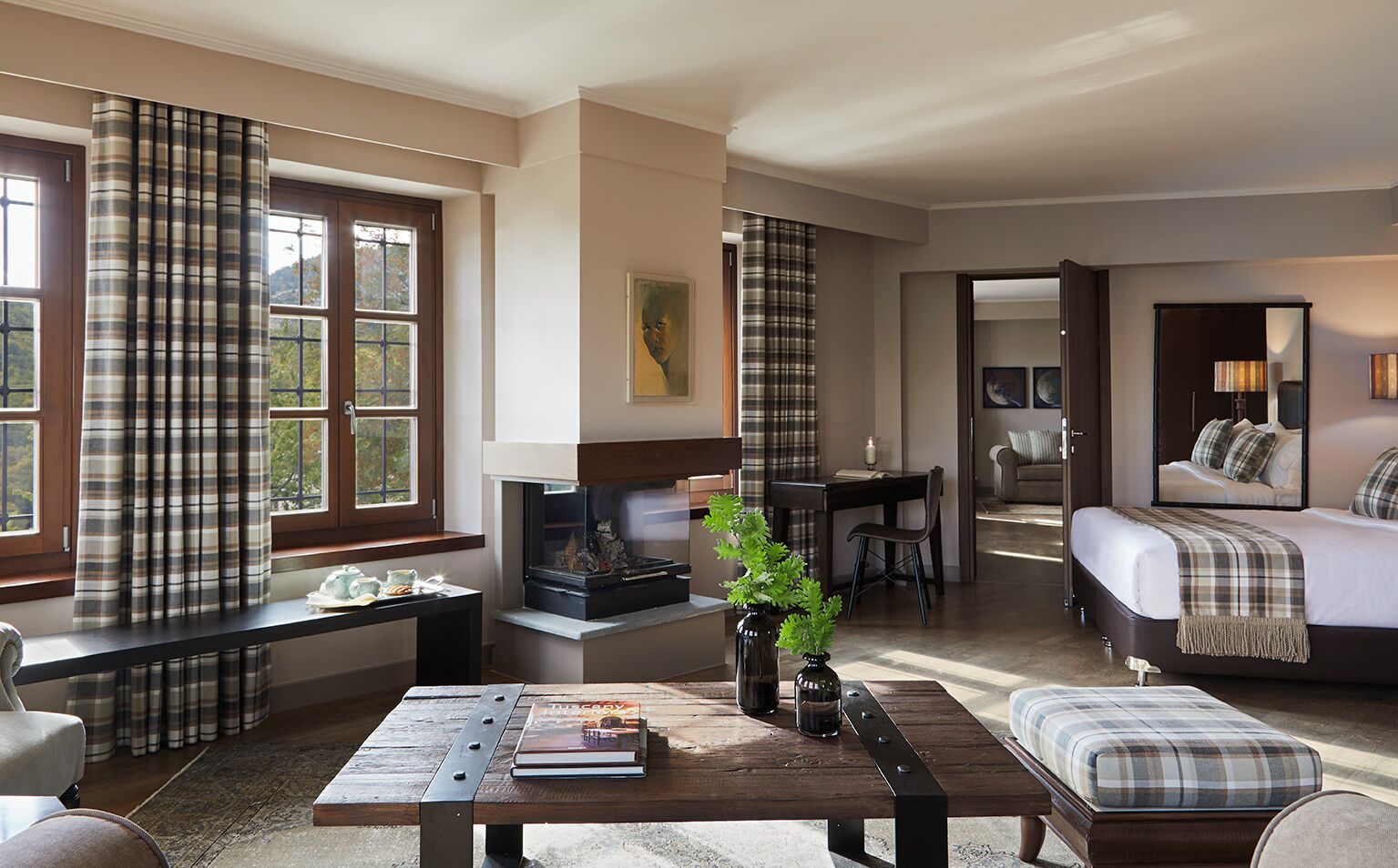 Una habitación de hotel acogedora con chimenea, zona de comedor, sofá y cama.