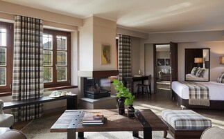 Una habitación de hotel acogedora con chimenea, zona de comedor, sofá y cama.