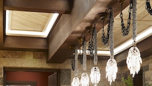 A bar area with wooden stools, a stone wall, and hanging crystal chandeliers. - MounTrace Suites & Spa (Zagori)