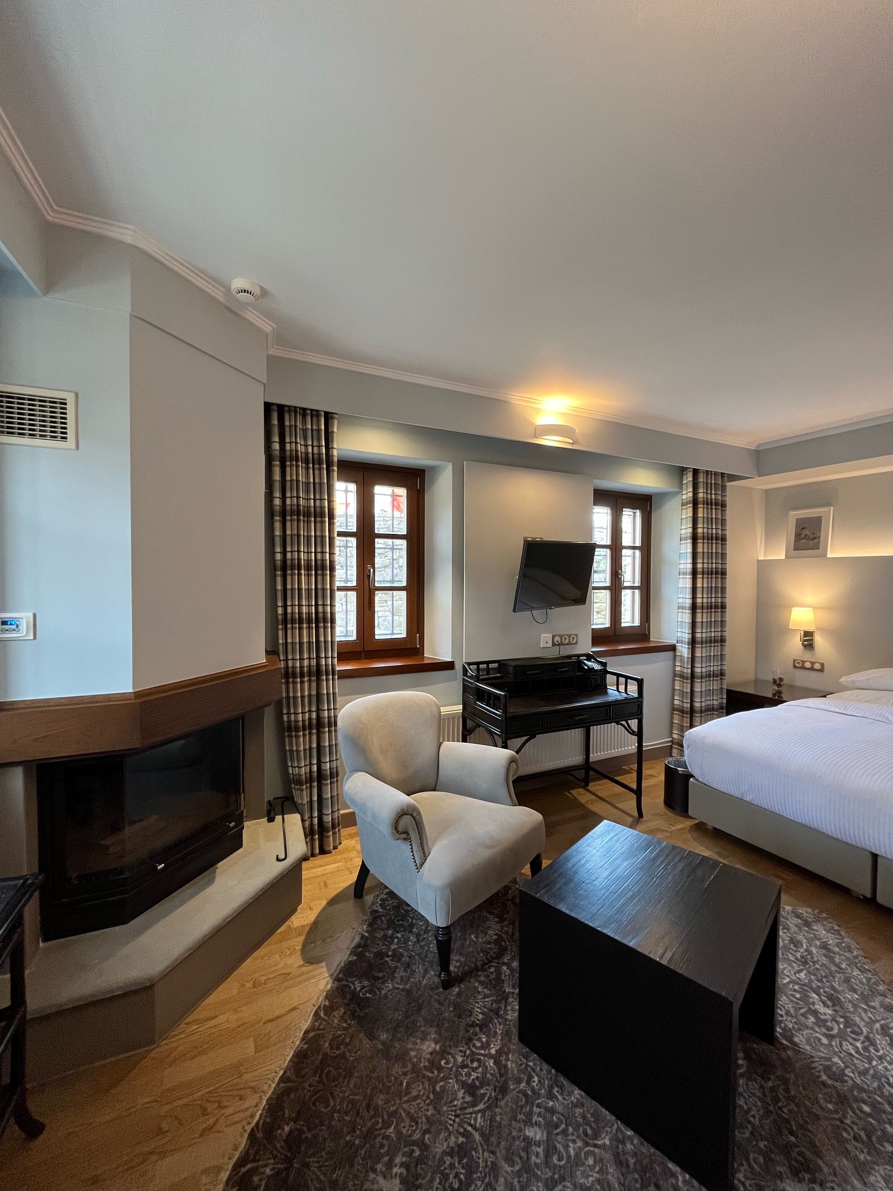 Una habitación de hotel con chimenea, un escritorio con computadora, una cama y un televisor.