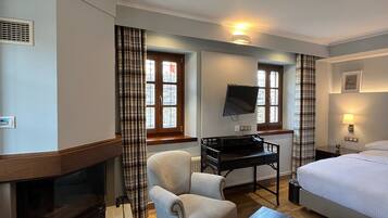Una habitación de hotel con chimenea, un escritorio con computadora, una cama y un televisor.