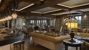 A spacious living area with a large sofa, a dining table, and a bar area. - MounTrace Suites & Spa (Zagori)