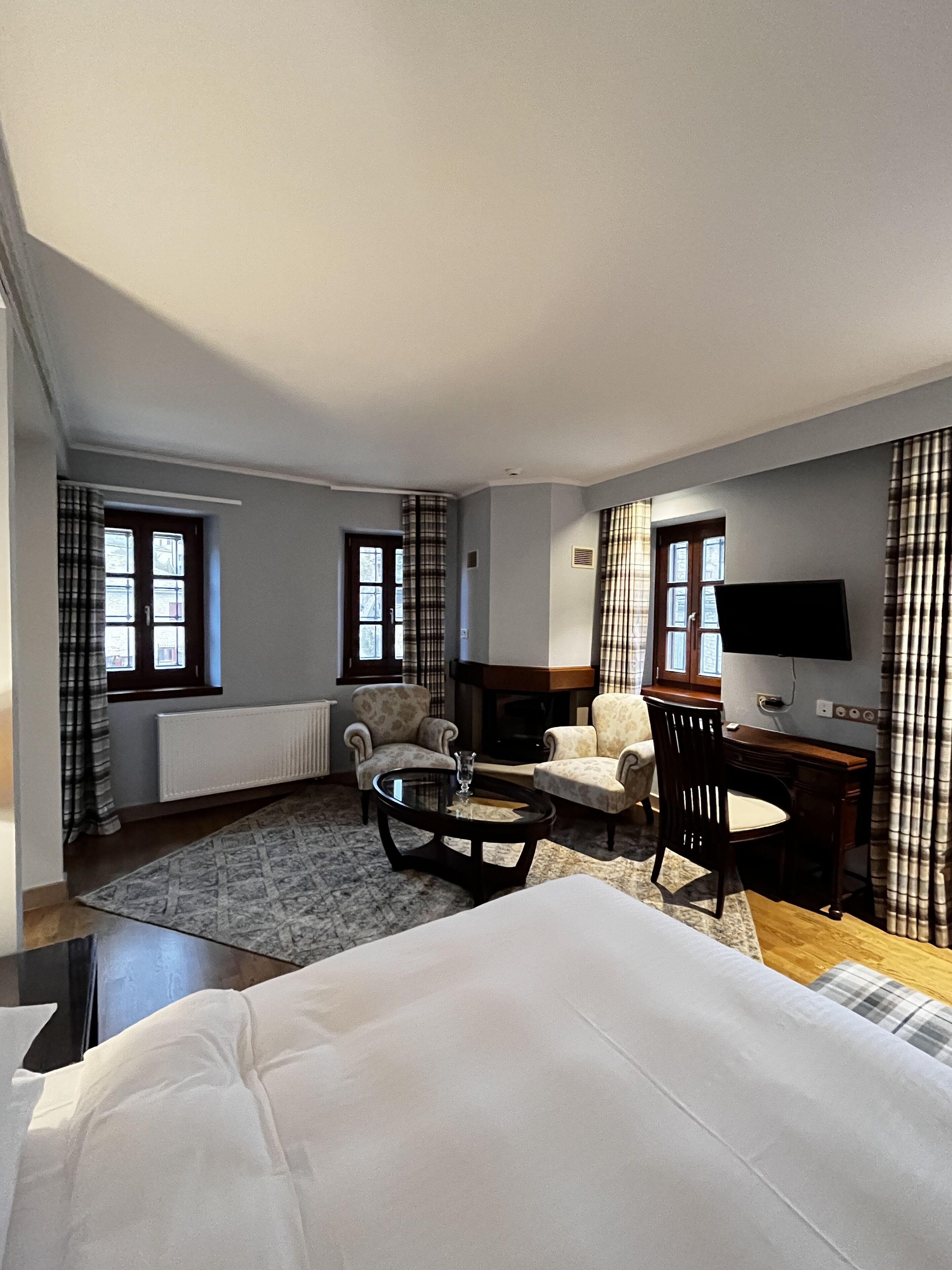 Ein Hotelzimmer mit einem Bett, zwei Sesseln, einem kleinen Tisch, einem Fernseher und einem Kamin.