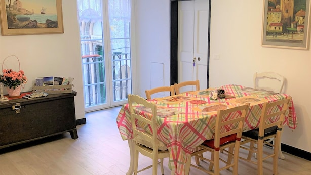 Ein Essbereich mit einem Tisch, der mit einer karierten Tischdecke bedeckt ist, umgeben von Holzstühlen. Eine Chandelier mit herzförmigen Lichtern hängt über dem Tisch.
