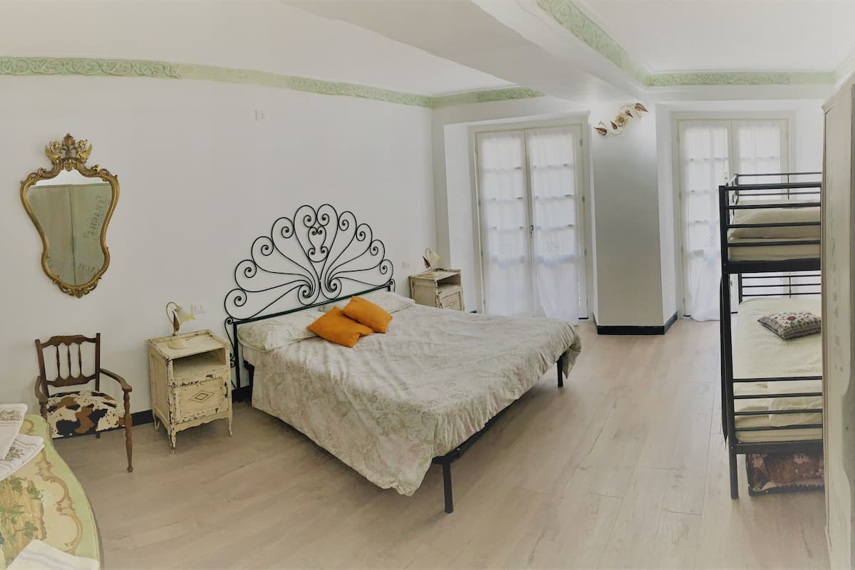 A bedroom with a bed, a nightstand, a chair, a mirror, and a window.