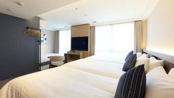 A hotel room with two beds, a desk with a TV, a chair, and a coat rack.