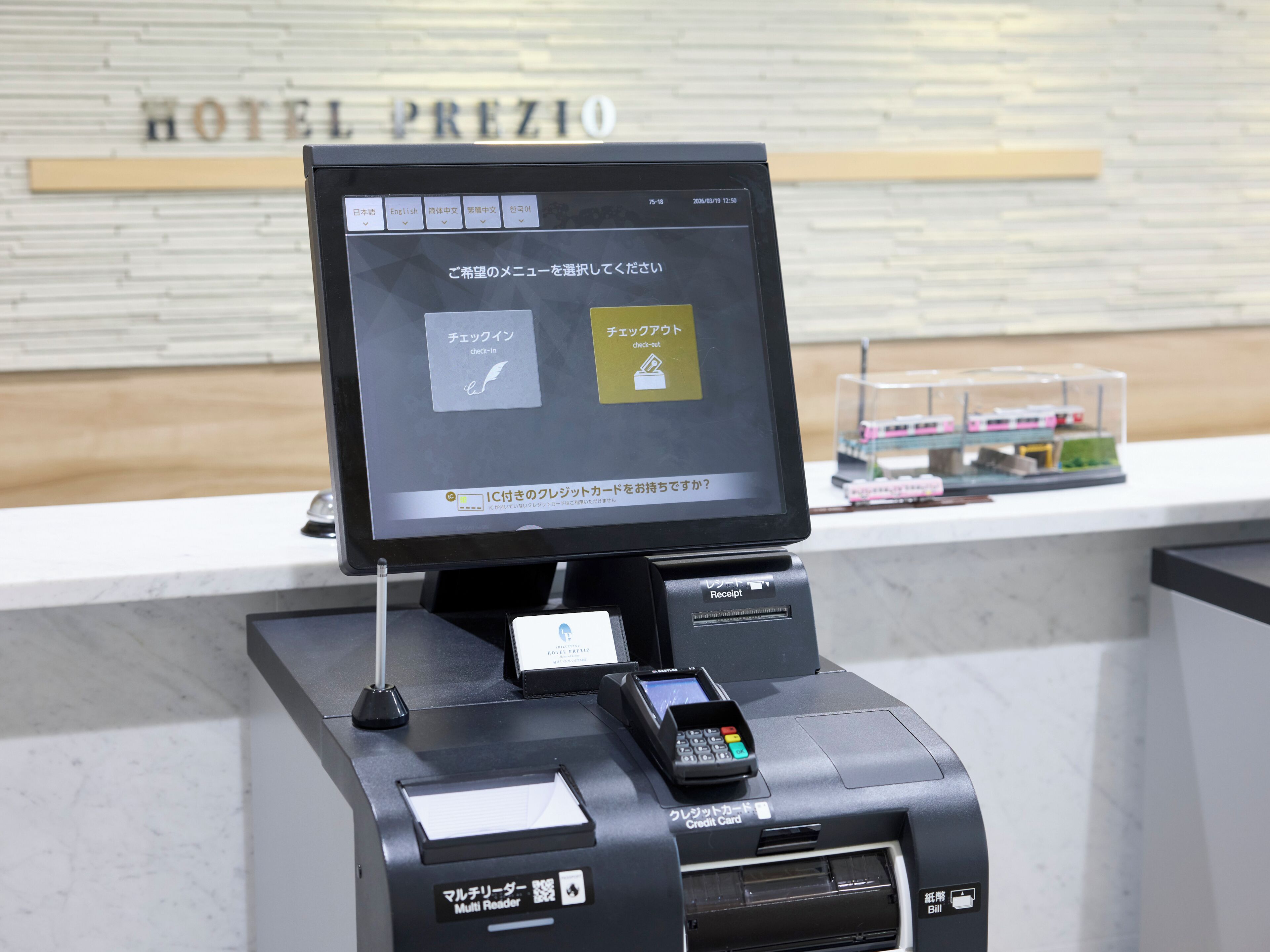 A hotel reception desk with a digital display, a credit card reader, and a multi-reader.