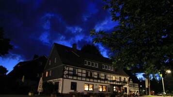 Ein traditionelles Gebäude mit dunkler Fassade und zahlreichen Fenstern, das an einer Straßenecke steht.