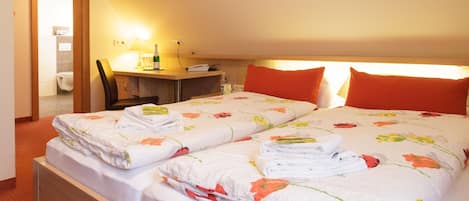 A hotel room with two beds, a desk, and a chair.