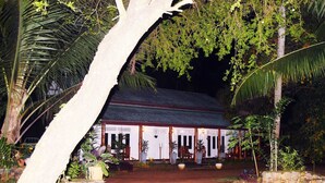 A traditional building with a thatched roof, surrounded by lush greenery and palm trees.