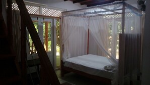 A bedroom with a four-poster bed, a wooden ladder, and a window with a white curtain.