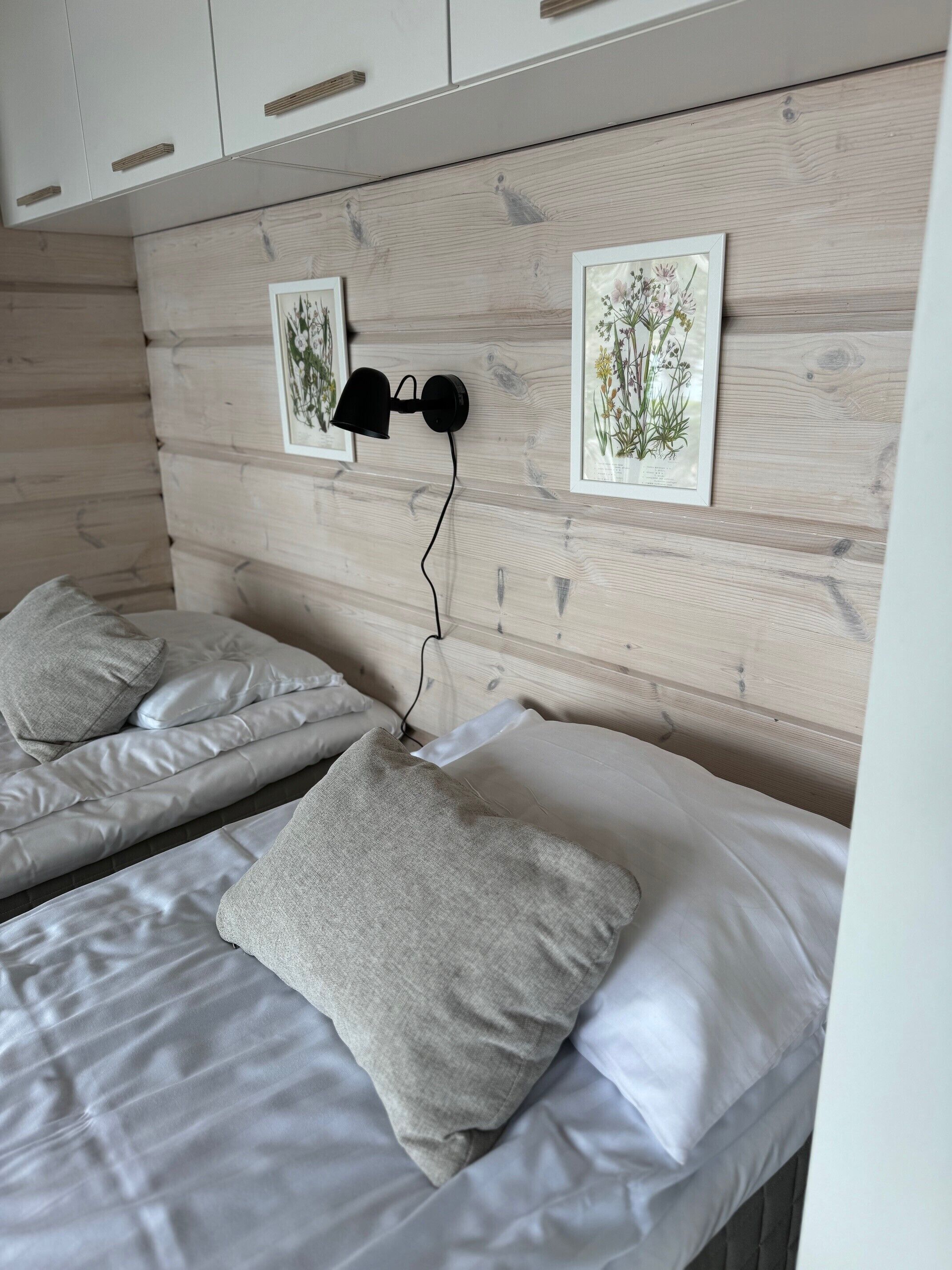 Een slaapkamer met twee bedden, elk voorzien van een kussen en een wandlamp.