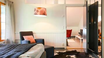 A modern bedroom with a bed, a chair, a cowhide rug, a television, and a wardrobe.