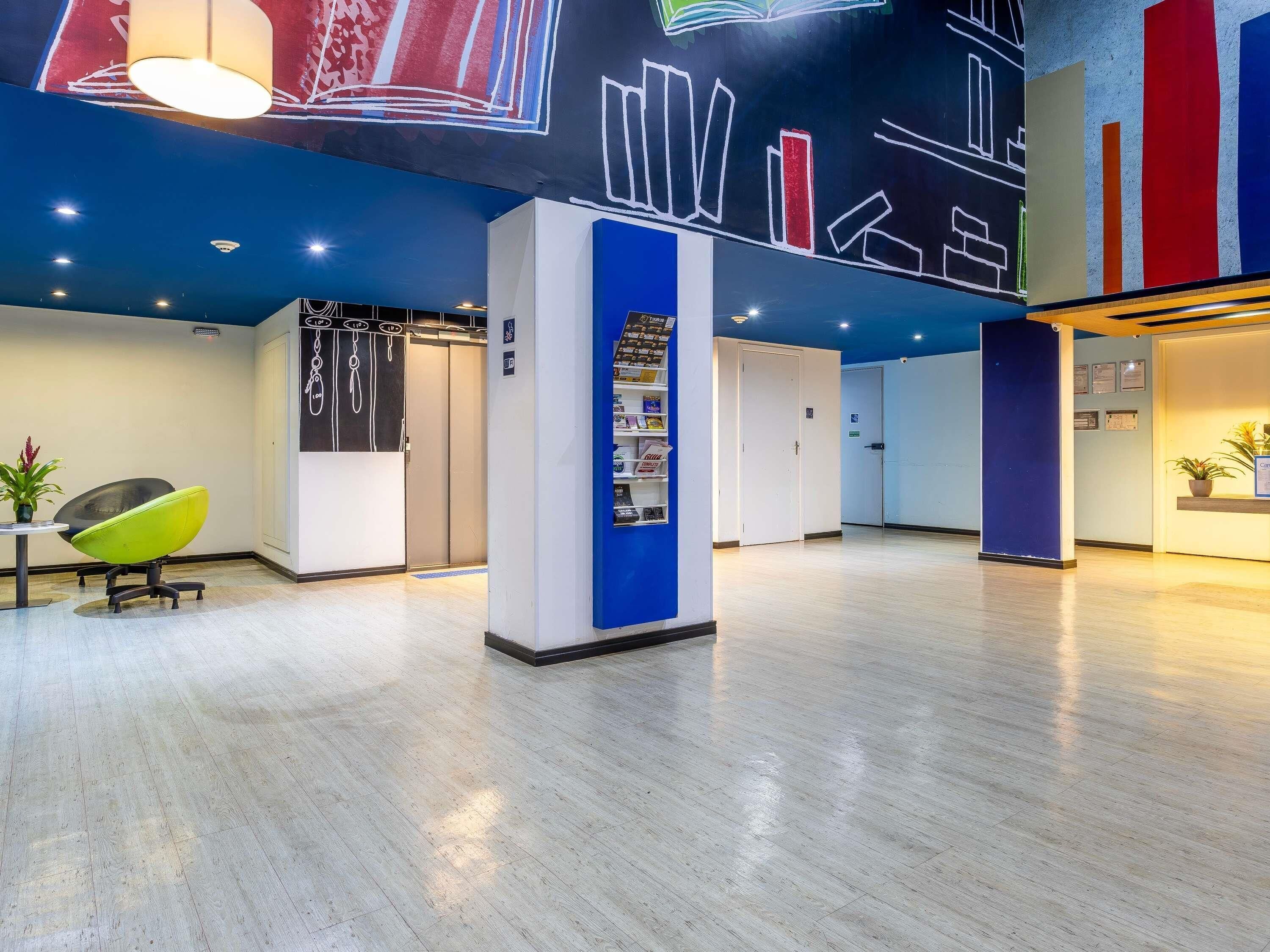 A spacious lobby with a reception desk, a blue pillar, and a green chair.