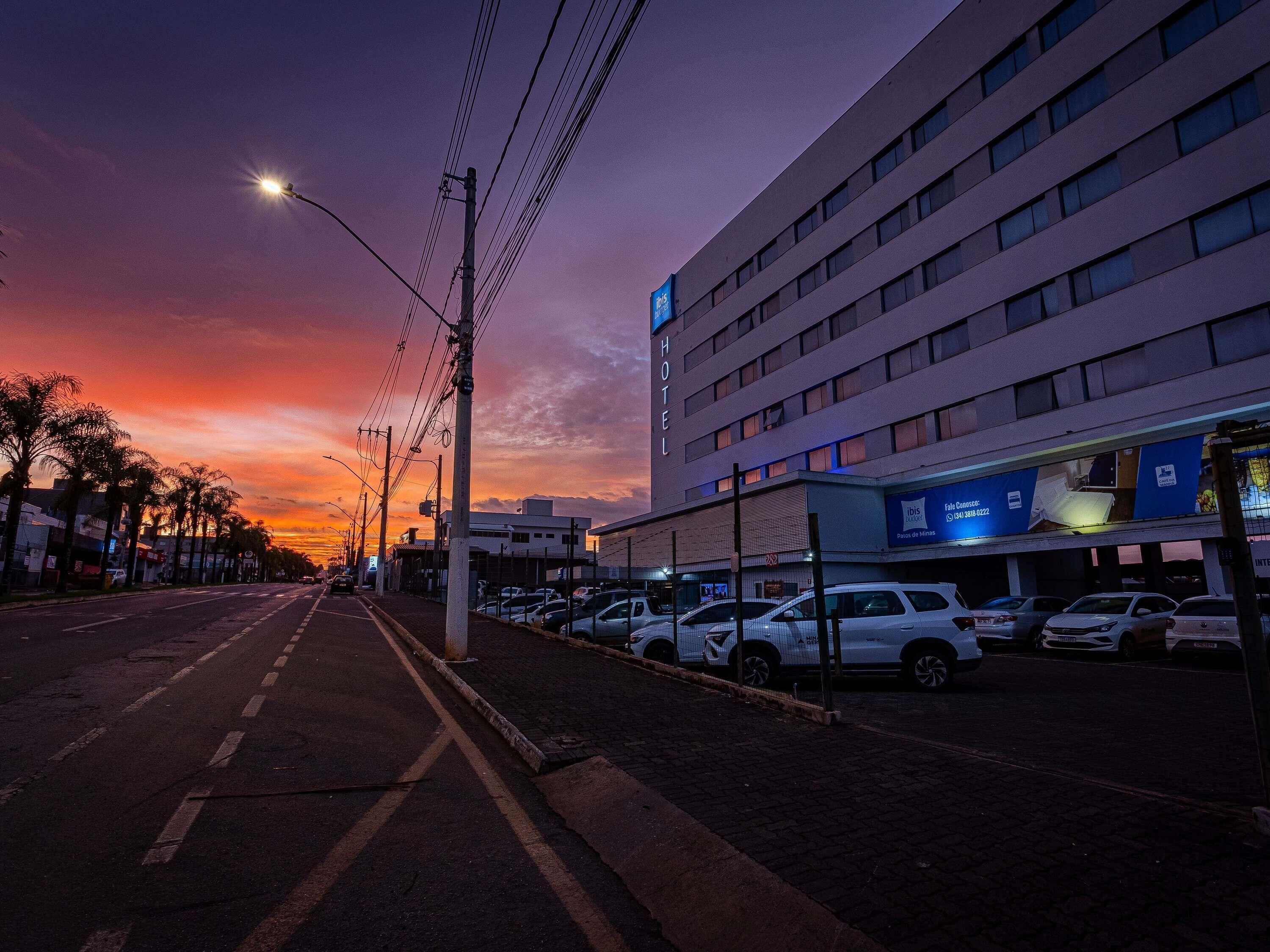 Un hotel de diseño moderno, un estacionamiento con coches y un cielo al atardecer.