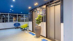 A modern office space with a large potted plant, a blue chair, and a blue mat on the floor. - ibis budget Patos de Minas (Patos de Minas)