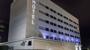 A multi-story hotel with a prominent 'HOTEL' sign on the facade, a 'ibis budget' sign above, and a modern architectural design with horizontal lines and illuminated windows. - ibis budget Patos de Minas (Patos de Minas)