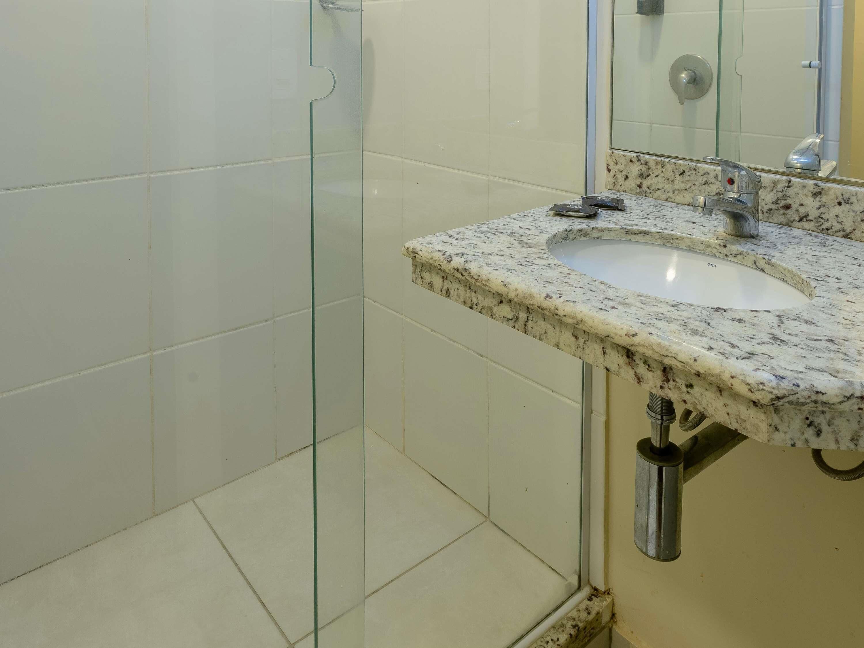 Un baño con cabina de ducha de vidrio, lavabo de mármol y espejo.