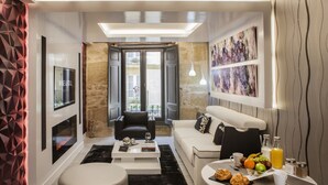 A modern living room with a sofa, coffee table, and dining area with breakfast items. - Wine & Soul Suites (Haro)