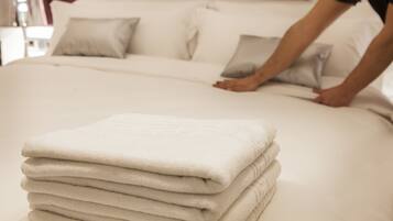A neatly made bed with a stack of folded towels in the foreground.