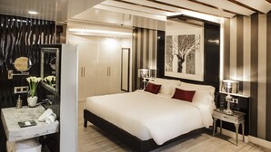 A modern bedroom with a large bed, bedside tables, a vanity with a mirror, and a framed artwork on the wall. - Wine & Soul Suites (Haro)