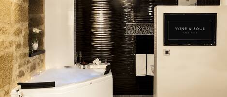 Un baño moderno con una bañera grande, una pared de piedra y un letrero que dice 'WINE & SOUL SUITES'.