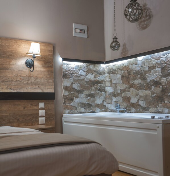 A bathroom with a stone wall, a sink, and a wall-mounted light fixture.