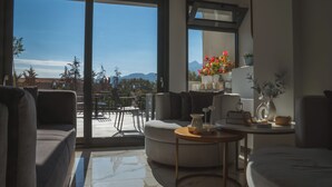 A modern living room with a sofa, a coffee table, and a view of the outdoors through large sliding doors. - Alkyonis Hotel & Spa (Almopia)