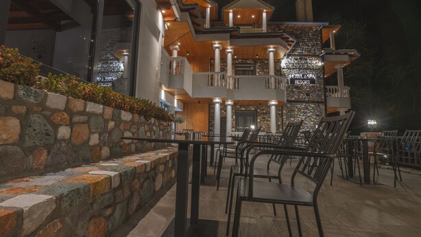 A hotel with multiple balconies, outdoor seating, and a stone facade. - Alkyonis Hotel & Spa (Almopia)