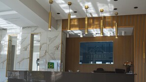 A hotel reception area with a marble-tiled floor, a reception desk, and a large framed sign above the desk. - Alkyonis Hotel & Spa (Almopia)
