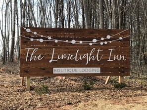A wooden sign with the text "The Luminight Inn Boutique Lodging" and decorative string lights.
