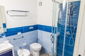Un baño con cabina de ducha de vidrio, inodoro y lavamanos.