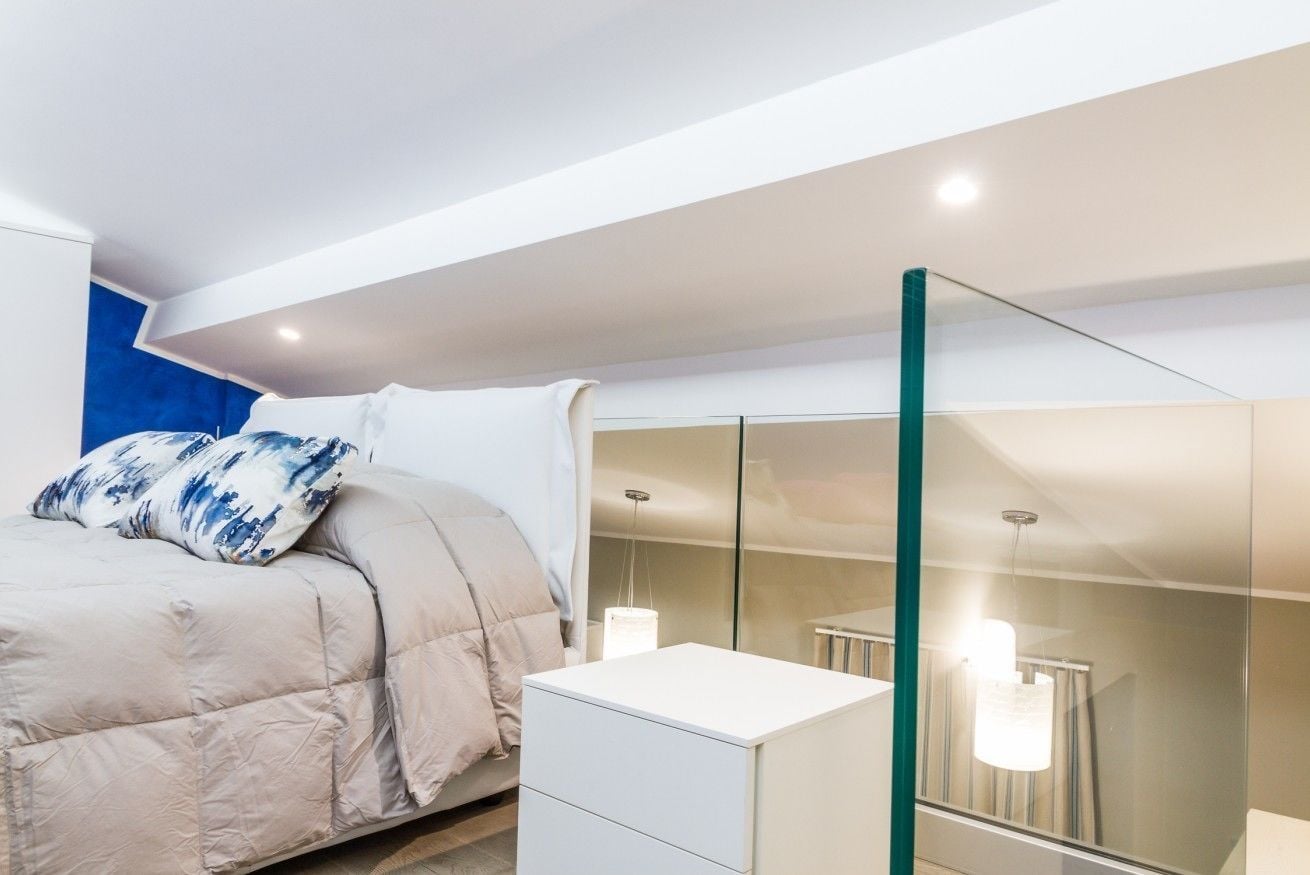 A modern bedroom with a bed, bedside table, and a large mirror.
