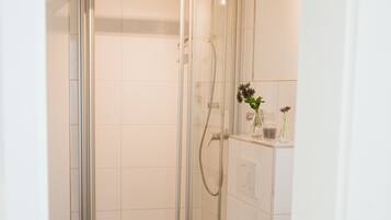 A modern bathroom with a glass-enclosed shower, a toilet, and a sink.