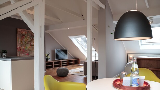 A modern kitchen with a dining area, a TV, and a skylight. - Glück Auf Appartements Rüttenscheiderstraße (Essen)