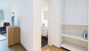 A modern, minimalistic room with a wooden desk, a white shelving unit, and a visible bathroom in the background. - Glück Auf Appartements Rüttenscheiderstraße (Essen)