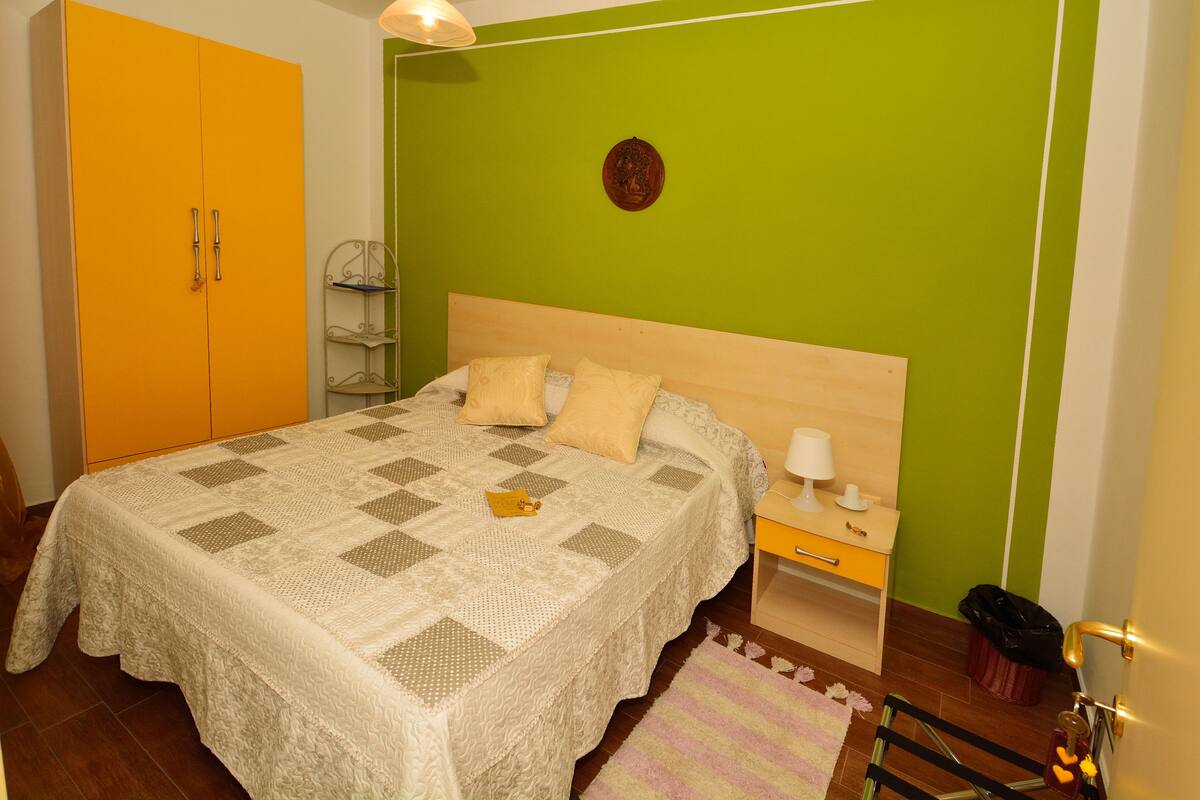 Ein Schlafzimmer mit Bett, Nachttisch, Lampe und Kleiderschrank.