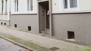 A multi-story residential building with a clean facade, multiple windows, and a visible door. - Glück Auf Appartements See Straße (Essen)