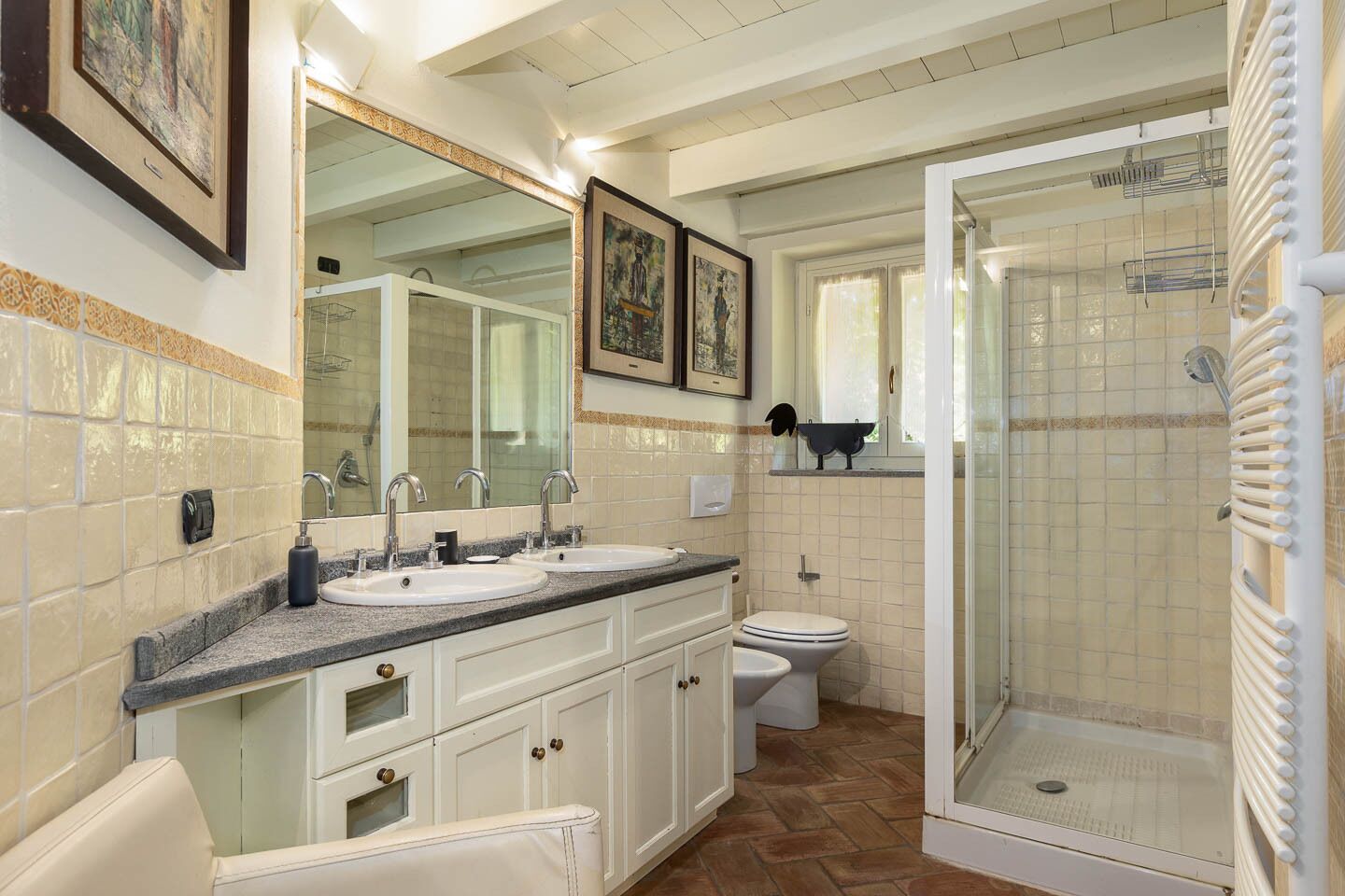 A bathroom with two sinks, a toilet, and a glass-enclosed shower.