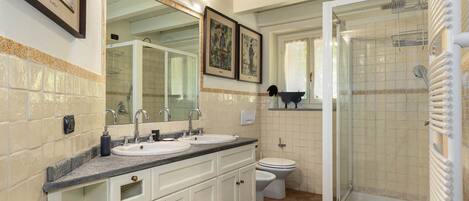 A bathroom with two sinks, a toilet, and a glass-enclosed shower.