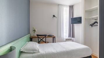 Une chambre à coucher avec un lit, un bureau avec une chaise, une télévision et une armoire.